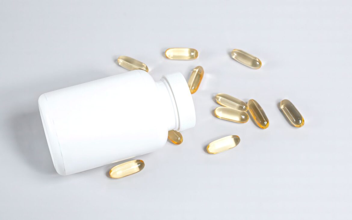 Healthy fish oil capsules spilled from a white bottle on a smooth white surface.