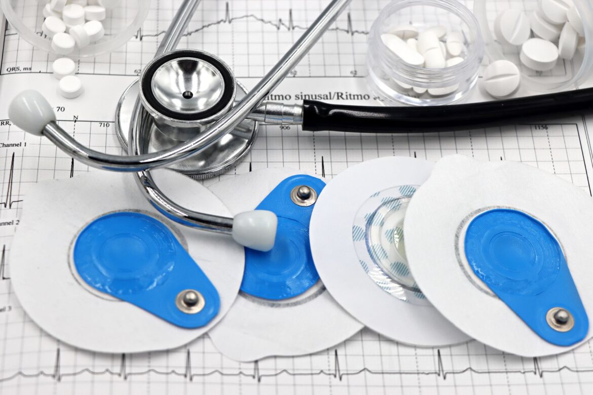 Medical instruments including stethoscope and ECG electrodes on a cardiology chart.