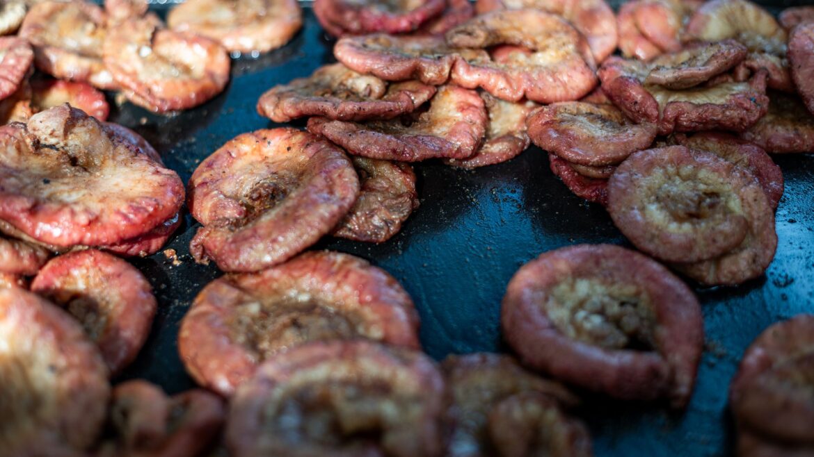 Close-up of traditional chinchulines grilling on an open parrilla, highlighting Argentinian cuisine.