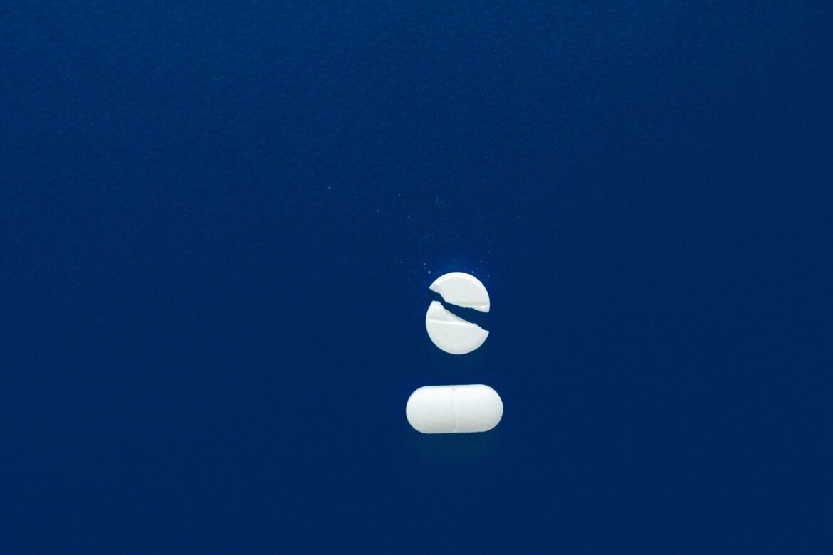 Broken pill with copy space on a blue background, symbolizing healthcare or medication concepts.