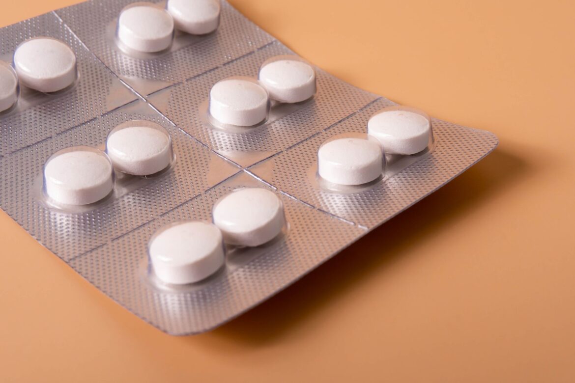 Close-up shot of white pills in a blister pack on a neutral background, ideal for healthcare themes.