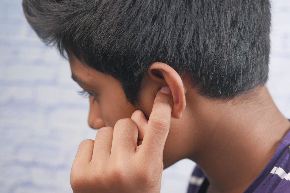Close-up of a teenager's profile with hand covering ear, reflecting introspection or concentration.