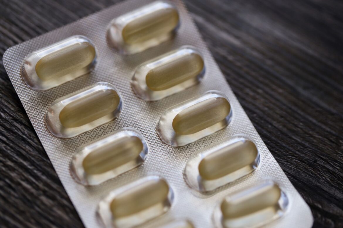 Detailed view of a blister pack with transparent capsules on a textured wooden background.