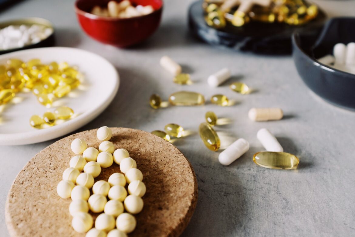 Close-up of assorted pills, capsules, and supplements on a marble surface, emphasizing healthcare and wellness.