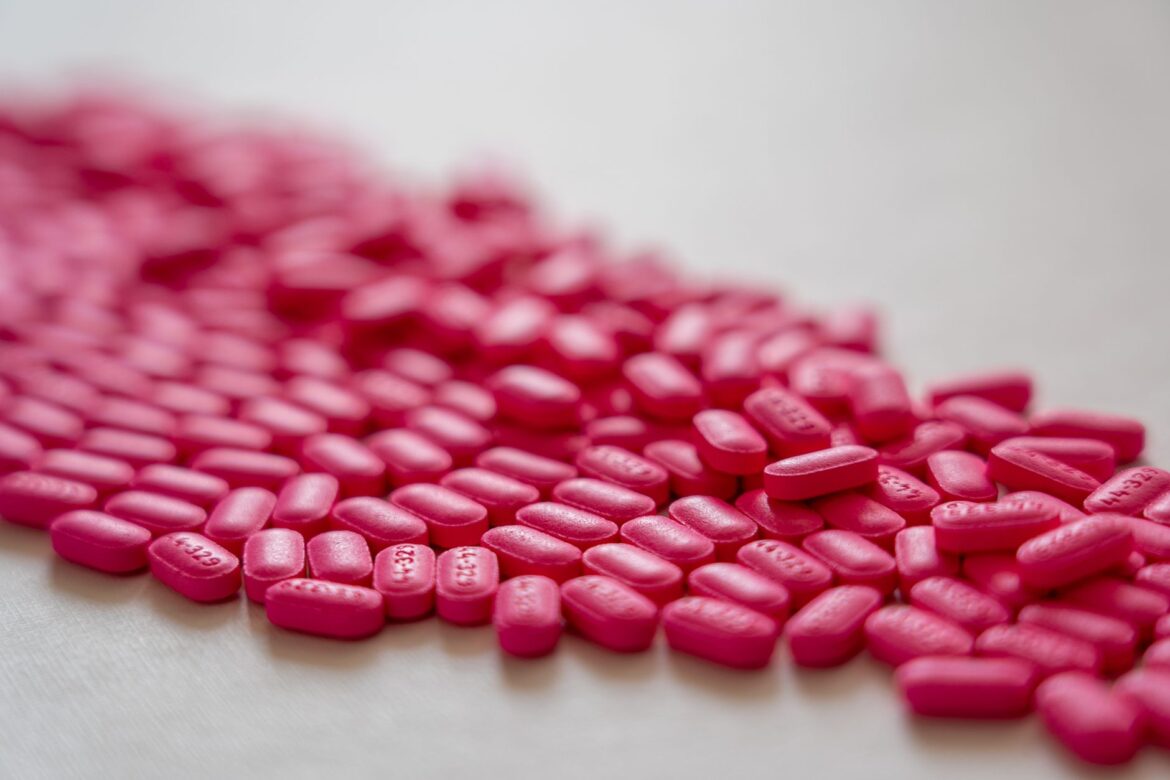 Bright neon pink pills spread on a table, creating a vibrant medical concept.