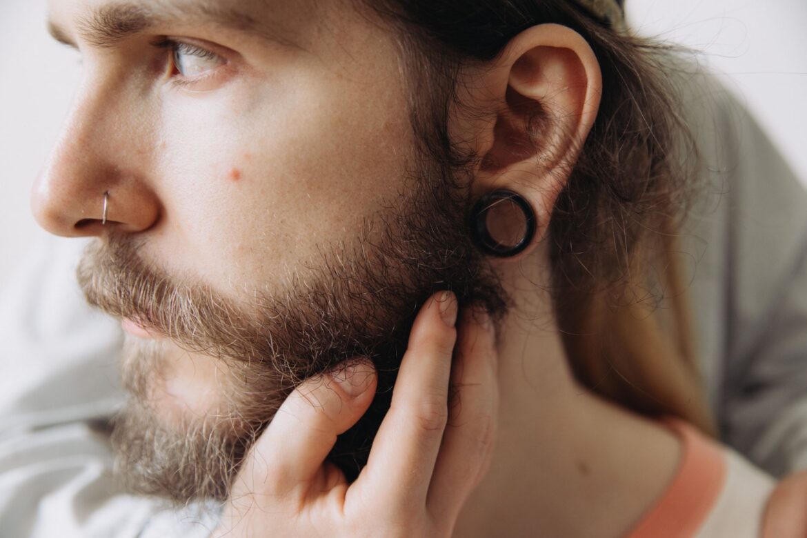 Close-up portrait of a man with a beard and earrings, showcasing personal style.
