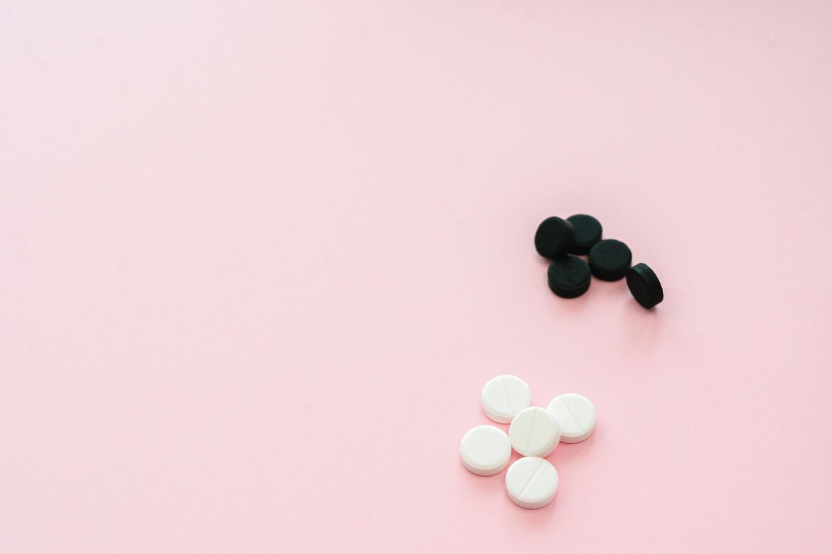 Assorted black and white tablets on a soft light pink background with ample copy space.